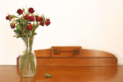 Red rose in vase on table against wall