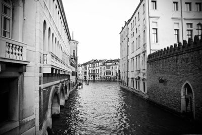 Canal amidst buildings against sky in city