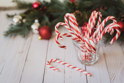 Glass full of candy canes against a christmas backdrop.