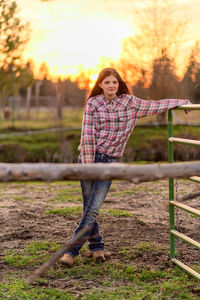 Portrait of young woman leaning on metal gate