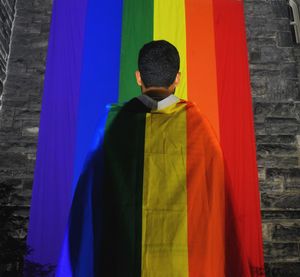 Young latino man with rainbow cape during pride parade lgbtqia  lgbtq