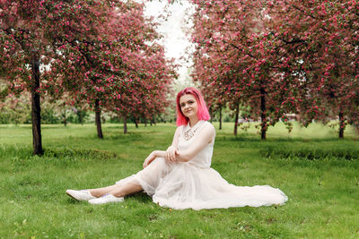 Young girl with pink hair in apple orchard.