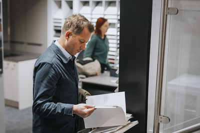 Side view of mature man reading brochure at electronics store