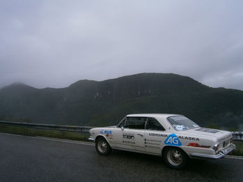 Side view of car on road against mountain range