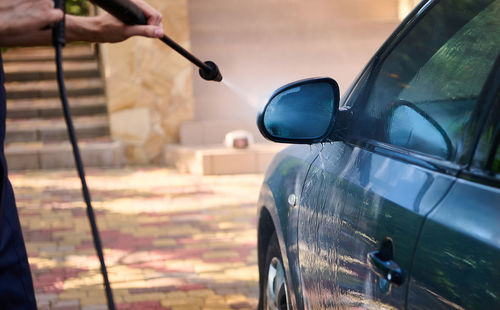 Cropped hand of man washing car