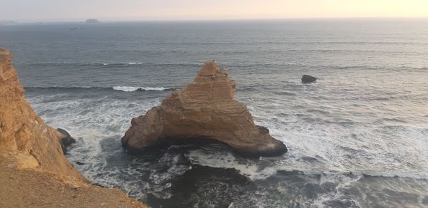 Rock formation on sea shore against sky