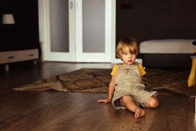 Little boy sitting on the carpet in the house