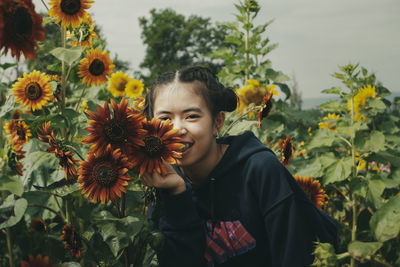 Portrait of young woman with sunflower on plant