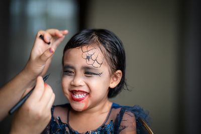 Mother painting daughters face. halloween party.
