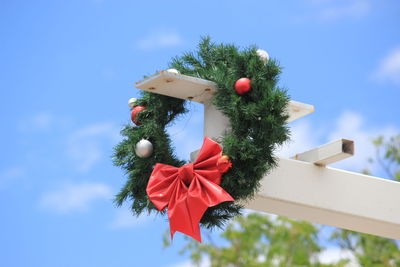 Low angle view of wreath hanging on metal against sky