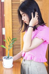 Midsection of woman holding pink potted plant on table