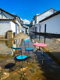 Empty chairs and houses against blue sky