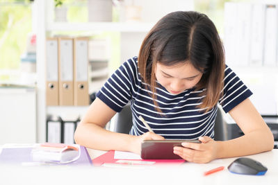 Young woman looking away while sitting on table