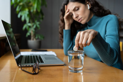 Unhealthy businesswoman taking painkiller from headache or migraine at workplace in office