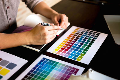 Midsection of businessman analyzing color swatches on table