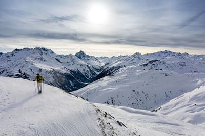 Rear view of person on snowcapped mountain against sky