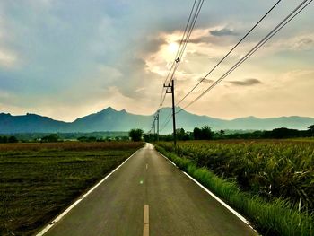 Road amidst field against sky