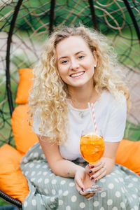 Portrait of a smiling young woman holding glass outdoors