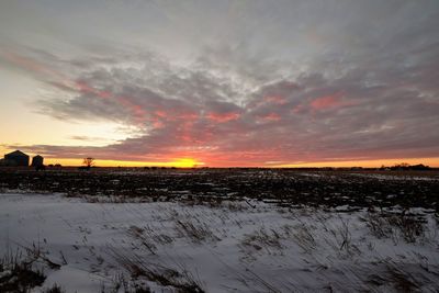 Scenic view of field against dramatic sky during sunset