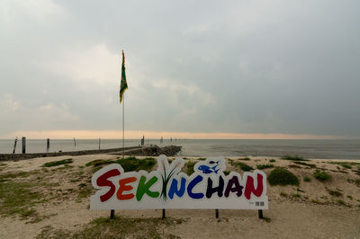 Information sign on beach against sky