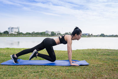 Side view of woman doing yoga by lake