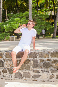 Full length of man sitting on wall