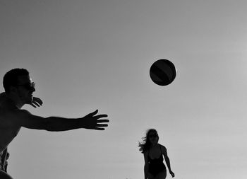 Woman playing with ball against clear sky