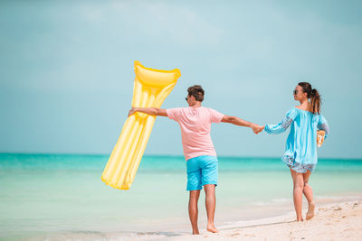 Couple walking on beach against sky