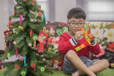 Boy playing by christmas tree at home
