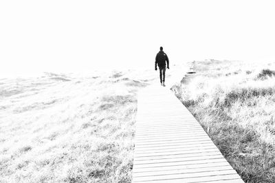 Rear view of man walking on street amidst sea