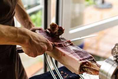 Midsection of man cutting meat