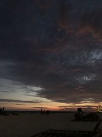 Silhouette people on beach against sky during sunset