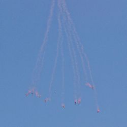 Low angle view of airshow against clear blue sky