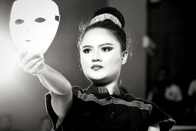 Young woman holding mask on stage