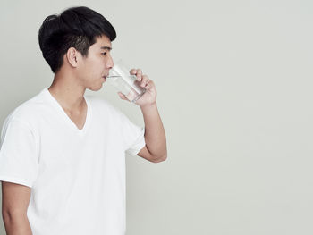 Young man smoking cigarette against white background
