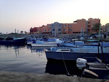 Boats moored in harbor against buildings in city