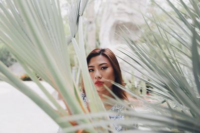 Portrait of young woman standing against plants in park