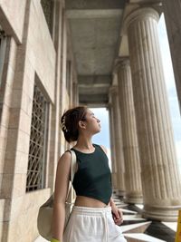 Rear view of young woman standing against building