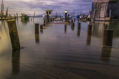 Wooden posts on pier by sea against sky