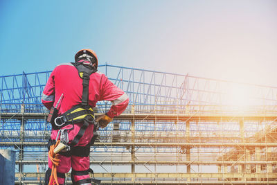 Man working on railing against clear sky