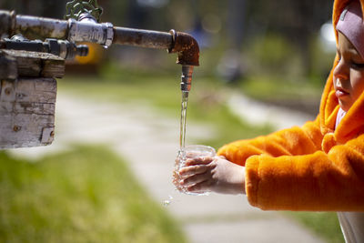 Cute girl filling water from faucet