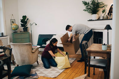 Couple unpacking boxes together in living room at new home