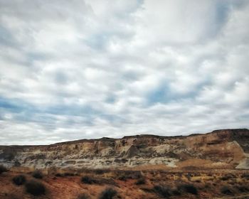Scenic view of desert against cloudy sky