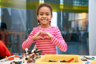 Smiling girl gesturing while playing with toys