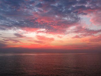 Scenic view of sea against dramatic sky during sunset