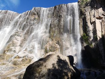 Low angle view of waterfall on rocks