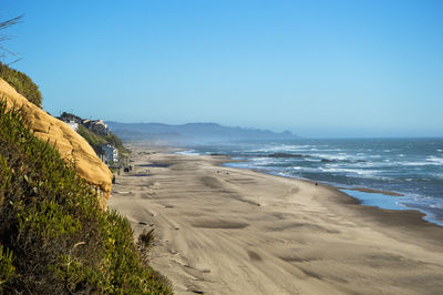 Scenic view of beach against clear blue sky