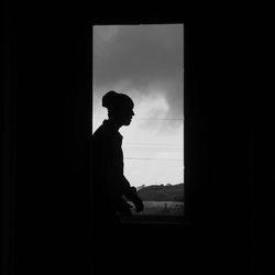 Side view of silhouette man standing against window