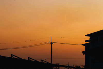 Low angle view of silhouette electricity pylon against romantic sky