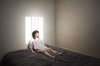 Woman sitting on bed against wall at home